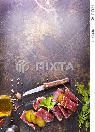 Dried Pastrami slices, beef meat with herbs on black board. 118673573