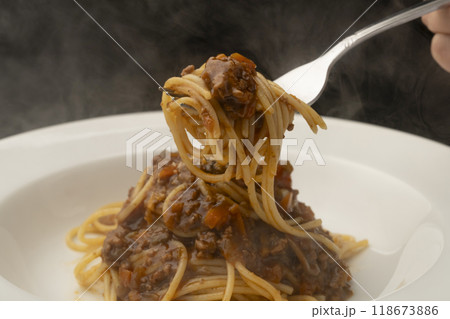 ミートソススパゲティ パスタをフォークで巻いて持ち上げる 118673886