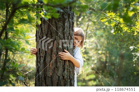 A teenage girl hugs a tree in the forest. 118674551