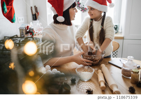 Mother and daughter baking together in festive kitchen Mother and daughter baking together in festive kitchen 118675339