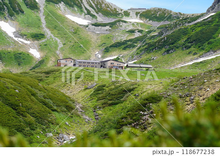 雪の残る夏の高原と山小屋 118677238