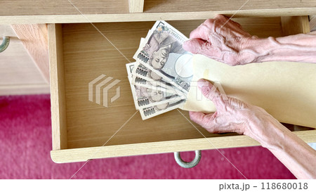 引出しを開けて封筒の中の1万円札5枚を広げる高齢女性の手元 引出しを開けて封筒の中の1万円札5枚を広げる高齢女性の手元 118680018