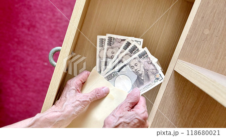 引出しを開けて封筒の中の5万円を広げる高齢女性の手元 引出しを開けて封筒の中の5万円を広げる高齢女性の手元 118680021