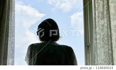 窓から青空を見上げる女性の後姿 118680024