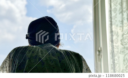 窓から青空を眺める女性の後姿 118680025