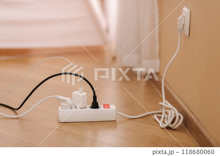 White cable connector for overloaded power boards at home. Close up focus at a plug foreground. White cable connector for overloaded power boards at home. Close up focus at a plug foreground. 118680060