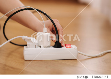Woman plugging the wire into white extension cord. Close up of female hand put cable Woman plugging the wire into white extension cord. Close up of female hand put cable 118680061