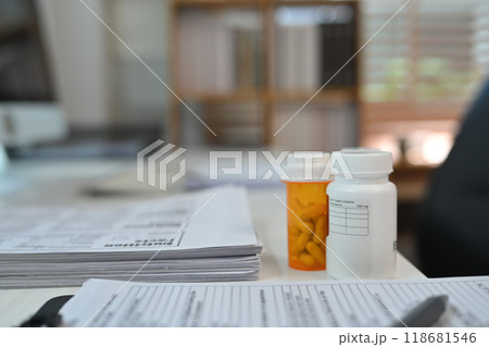 Close up shot of prescription pill bottles and medical document on table. Healthcare and medication concept Close up shot of prescription pill bottles and medical document on table. Healthcare and medication concept 118681546