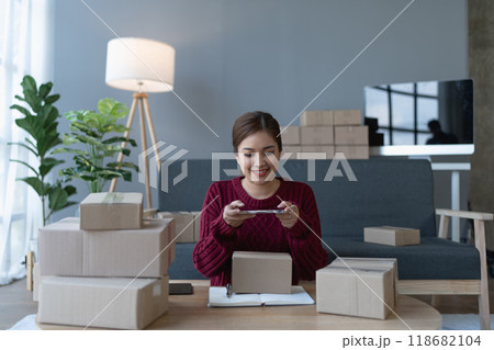 woman, online seller, uses her smartphone to take a photo of a product and address customer inquiries, ensuring satisfaction in her e-commerce business 118682104