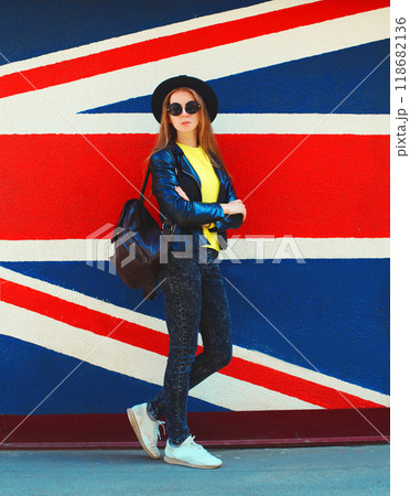 Portrait of beautiful young woman posing on english flag wall background 118682136