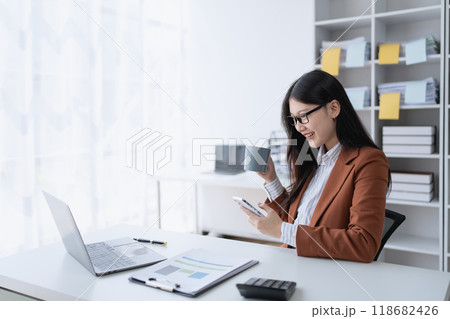 A businesswoman takes a break from her financial tasks, relaxing with a cup of coffee to recharge before continuing her work. 118682426