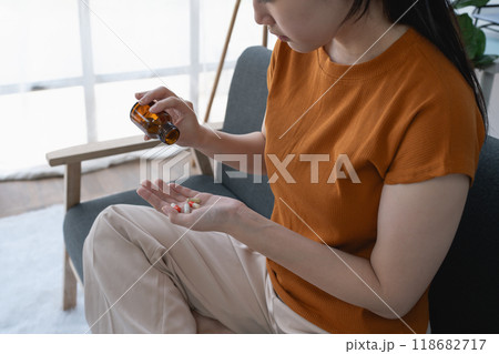 The woman, sitting on the sofa at home, stared at the medicine bottle, a symbol of her battle with depression The woman, sitting on the sofa at home, stared at the medicine bottle, a symbol of her battle with depression 118682717