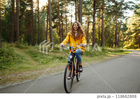 Young woman in yellow coat riding bicycle park. Active day. Young woman in yellow coat riding bicycle park. Active day. 118682808