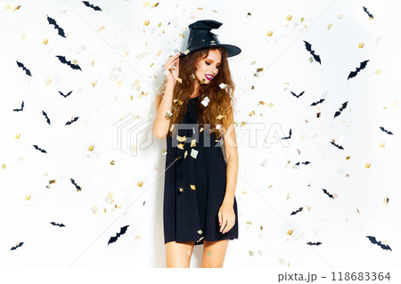 happy young woman in black witch halloween costume on party over white background with bats. happy young woman in black witch halloween costume on party over white background with bats. 118683364
