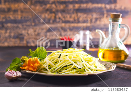 Raw zucchini noodles on plate. Zucchini spaghetti in metal bowl. Raw zucchini noodles on plate. Zucchini spaghetti in metal bowl. 118683487