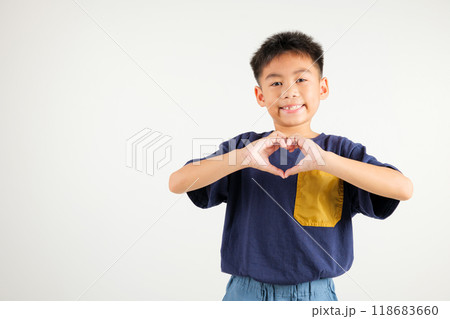 A smiling Asian young kid boy shows confidence, creating a heart shape with fingers and hands on white background. Portrait of primary child sending love for Valentine's Day A smiling Asian young kid boy shows confidence, creating a heart shape with fingers and hands on white background. Portrait of primary child sending love for Valentine's Day 118683660