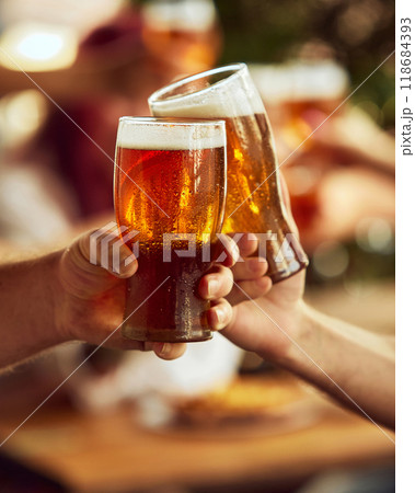 Two hands clink glasses and foam spilling over. Blurred cheering fans in background elevate celebratory spirit. Selective focus. 118684393