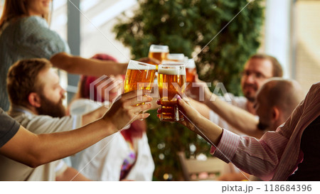 Beers held high in toast of triumph. Background fades into blur, keeping focus on emotions shared among fans. Friends drinks alcohol and celebrating. 118684396