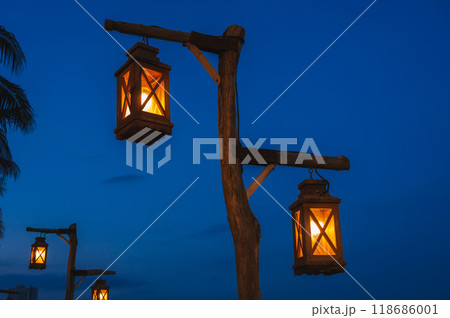 An old street lamp on a lamppost illuminating a dark street An old street lamp on a lamppost illuminating a dark street 118686001