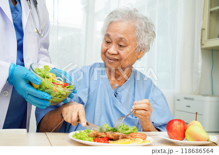 Asian elderly woman patient eating salmon stake and vegetable salad for healthy food in hospital. 118686564