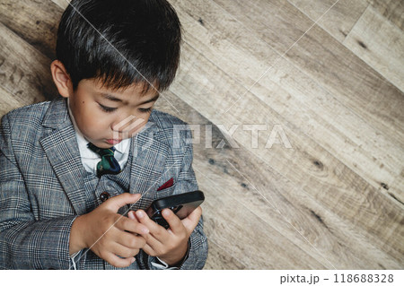 スーツ姿でスマートフォンを操作している子ども 118688328