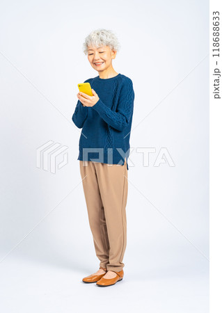 笑顔でスマホを使うシニア女性の全身写真 笑顔でスマホを使うシニア女性の全身写真 118688633