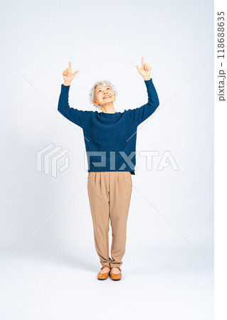 上を指さしてアピールするシニア女性の全身写真 上を指さしてアピールするシニア女性の全身写真 118688635