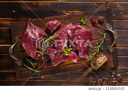 Raw meat with herbs and garlic, marble meat. Wooden background. Top view. Raw meat with herbs and garlic, marble meat. Wooden background. Top view. 118689102