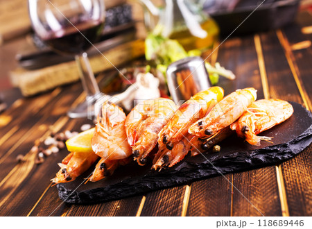 Fried shrimps with garlic, lemon served on black plate on wooden table Fried shrimps with garlic, lemon served on black plate on wooden table 118689446