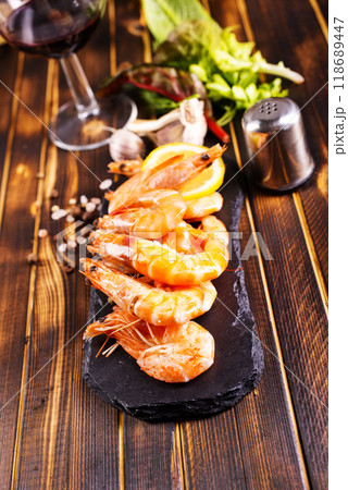 Fried shrimps with garlic, lemon served on black plate on wooden table Fried shrimps with garlic, lemon served on black plate on wooden table 118689447