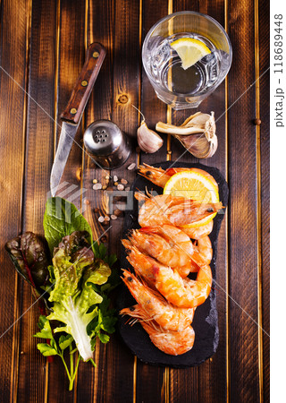 Fried shrimps with garlic, lemon served on black plate on wooden table Fried shrimps with garlic, lemon served on black plate on wooden table 118689448