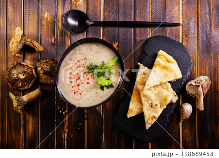 Bowl of creamy mushroom soup, sliced mushrooms and parsley with bread 118689458