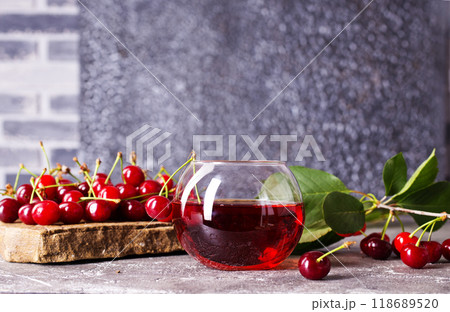 Cherry juice in a glass and fresh cherries on a table Cherry juice in a glass and fresh cherries on a table 118689520