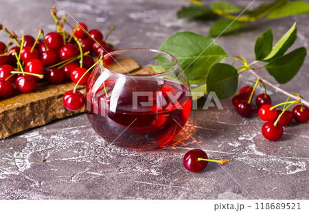Cherry juice in a glass and fresh cherries on a table Cherry juice in a glass and fresh cherries on a table 118689521