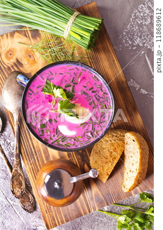 A portion of beetroot soup with egg, dill, parsley and cucumber on a gray background. A portion of beetroot soup with egg, dill, parsley and cucumber on a gray background. 118689612