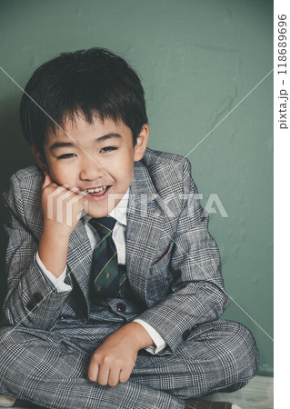 頬杖をついて座るスーツ姿の無邪気な子ども 118689696