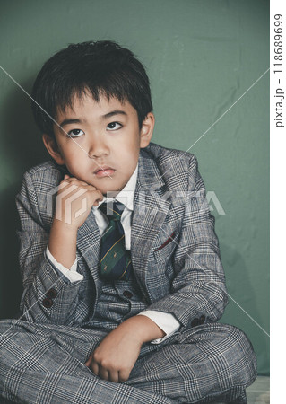 頬杖をついて座るスーツ姿の無邪気な子ども 118689699