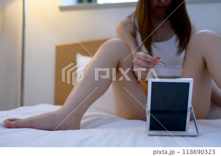 VIOデリケートゾーン股間のセルフケアをする若い女性　鏡を見ながらピンセットで毛抜き　暗め寒色 118690323