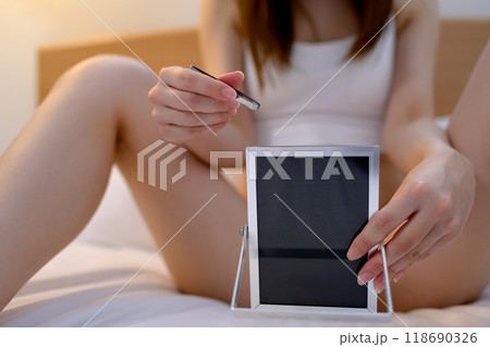 VIOデリケートゾーン股間のセルフケアをする若い女性 鏡を見ながらピンセットで毛抜き ネガティブ暗め VIOデリケートゾーン股間のセルフケアをする若い女性 鏡を見ながらピンセットで毛抜き ネガティブ暗め 118690326