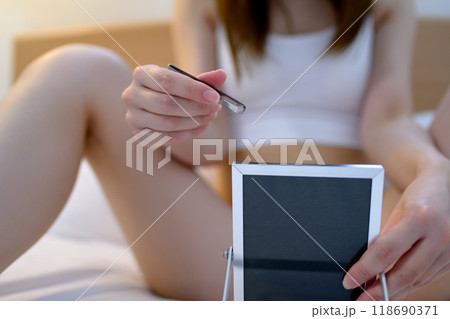 VIOデリケートゾーン股間のセルフケアをする若い女性 鏡を見ながらピンセットで毛抜き 暗め寒色 VIOデリケートゾーン股間のセルフケアをする若い女性 鏡を見ながらピンセットで毛抜き 暗め寒色 118690371