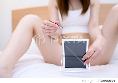 VIOデリケートゾーン股間のセルフケアをする若い女性　鏡を見ながらピンセットで毛抜き　リアルカラー 118690634