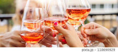 Close-up many female woman hands hold clinking rose wine glass celebrate toast party terrace warm sunset sun background. Girl friend enjoy drink champagne cocktail bachelorette event outdoor cafe bar 118690929