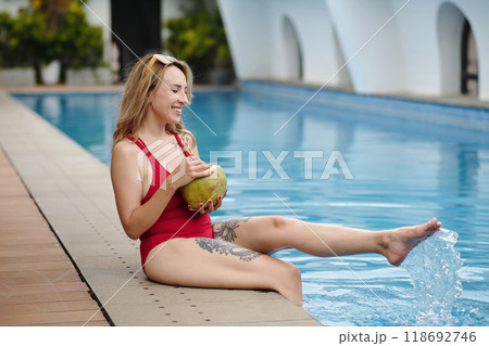 Relaxing by Poolside Holding Fresh Coconut Drink 118692746
