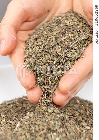 Seasoning dried basil in human hands, handful of chopped basil close-up 118692869