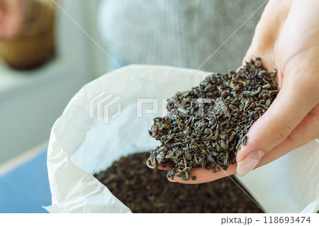 Woman holding paper bag with dry green tea leaves, close up 118693474