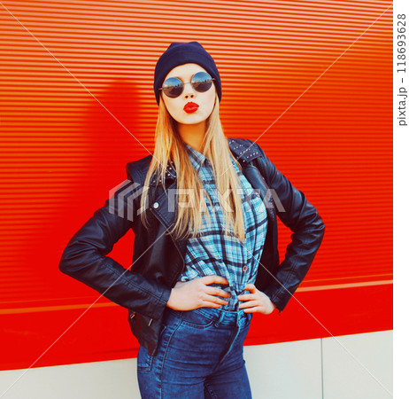 Fashion portrait beautiful blonde woman sends air kiss blowing red lips outdoors wearing sunglasses and black hat Fashion portrait beautiful blonde woman sends air kiss blowing red lips outdoors wearing sunglasses and black hat 118693628