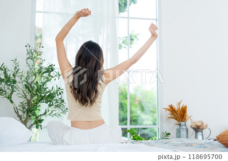 Back of young beautiful Asian woman wake up and stretch oneself on bed in the morning with happiness. Back of young beautiful Asian woman wake up and stretch oneself on bed in the morning with happiness. 118695700