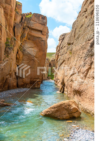 Kuljabashi Canyon on the way to kelsuu lake located in Kyrgyzstan, a narrow beautiful canyon with orange stones and a blue river Kuljabashi Canyon on the way to kelsuu lake located in Kyrgyzstan, a narrow beautiful canyon with orange stones and a blue river 118696850