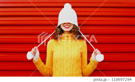 Portrait happy young smiling woman wearing a colorful knitted yellow sweater over red background Portrait happy young smiling woman wearing a colorful knitted yellow sweater over red background 118697294
