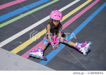A girl upset by a roller skating failure. A child in a helmet and full sports gear 118698642